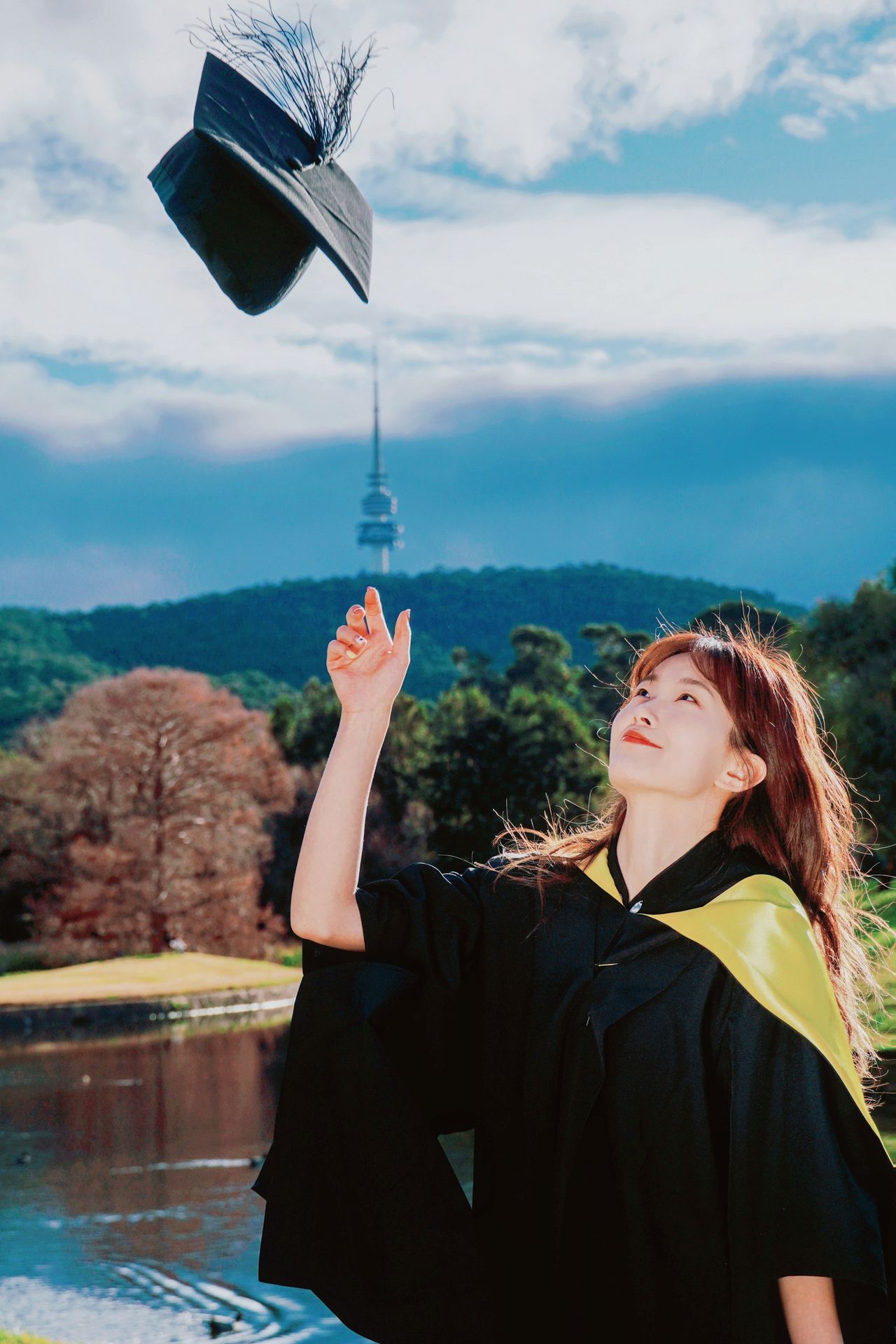 A woman in a graduation gown throwing a hat into the air